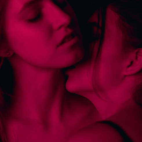 Woman enjoys another woman kissing her neck