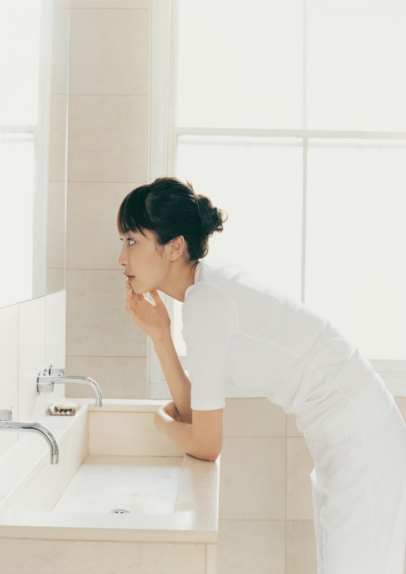 woman looking in mirror white bathroom