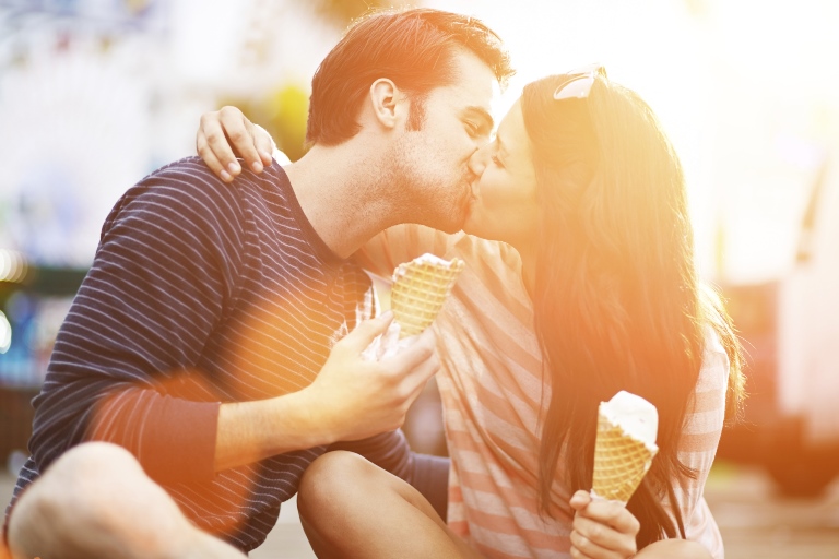 Man and woman kiss with ice cream cones