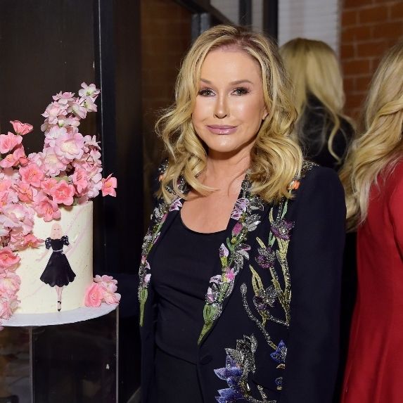 Kathy Hilton standing beside a lavish cake.