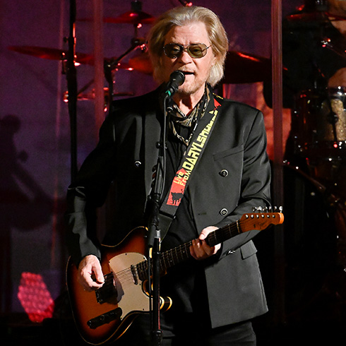Daryl Hall playing guitar and singing into microphone