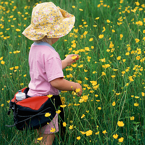 Girl with fanny pack picking flowers in field