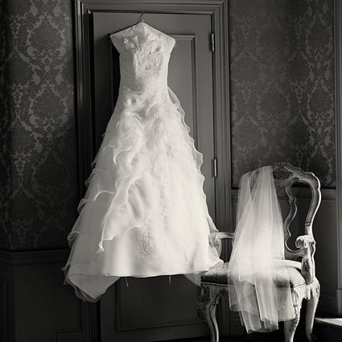 Wedding dress hanging on wall next to veil
