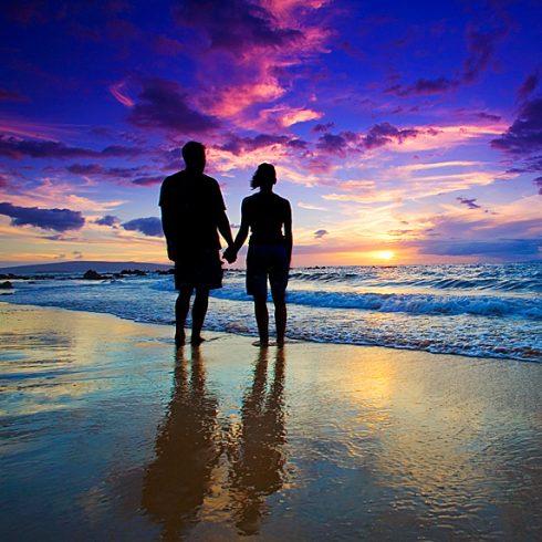 Couple on beach looking at stunning sunset