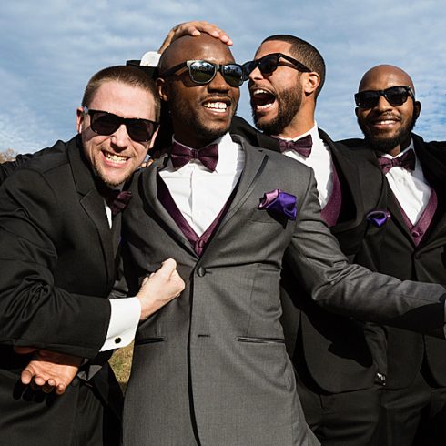 Groom laughing with three groomsmen