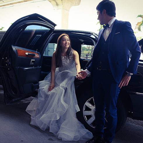 Groom helping bride out of car