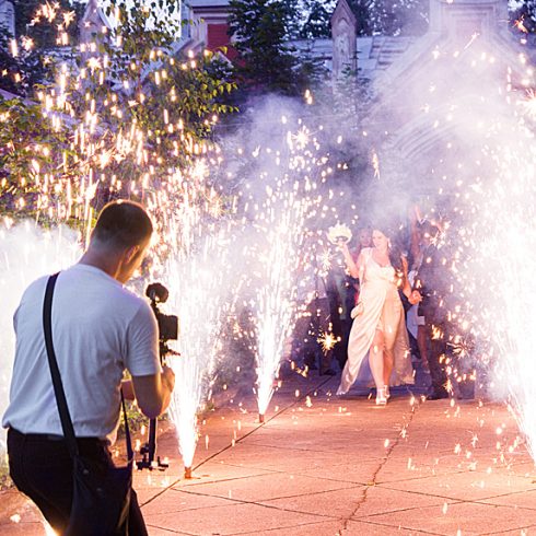 Videographer shooting bride and groom amidst pyrotechnics