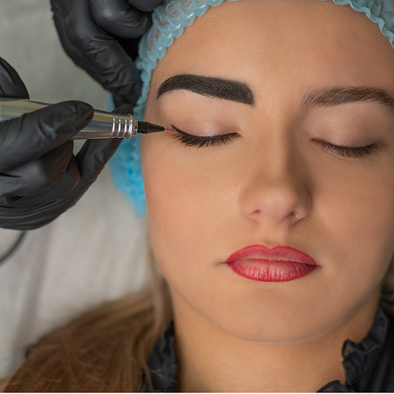 young woman having winged liner tattooed permanently