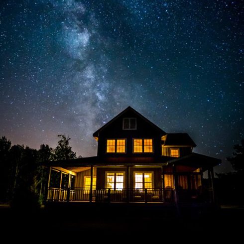 House lit up from inside, against a starry sky