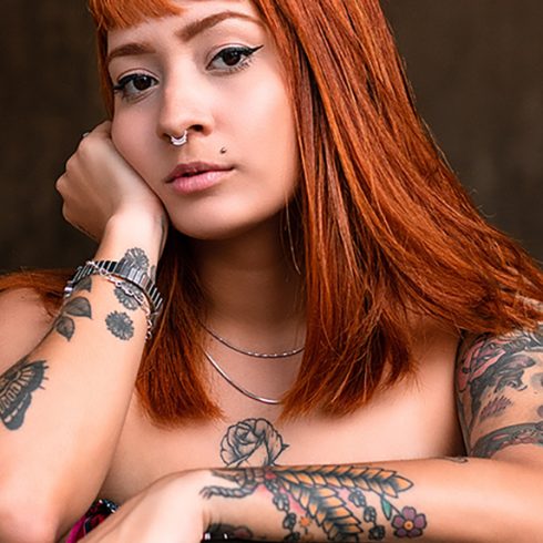 a young redheaded woman with tattoos looking at the camera