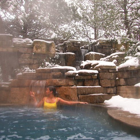A woman enjoys the outdoor hot springs pool at 100 Fountain Spa