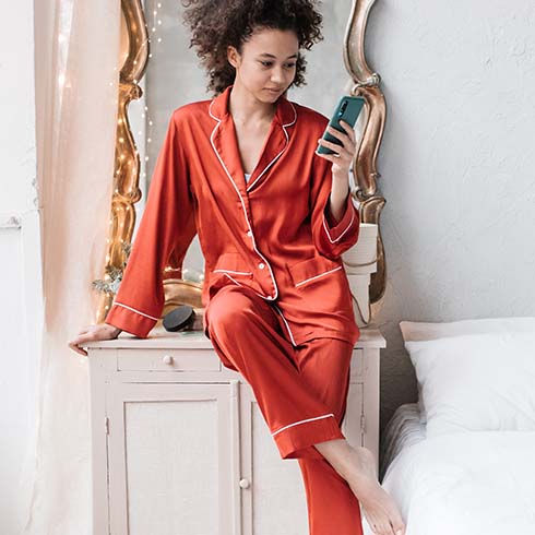 Black woman wearing red pajamas holding phone