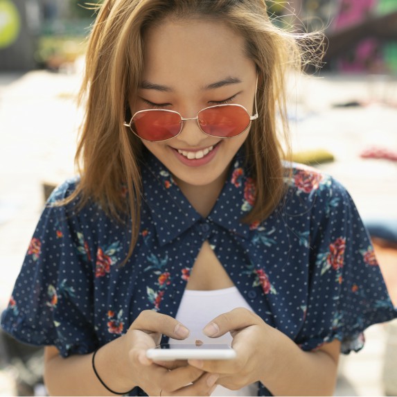 Stylish Asian girl checks her phone with big smile