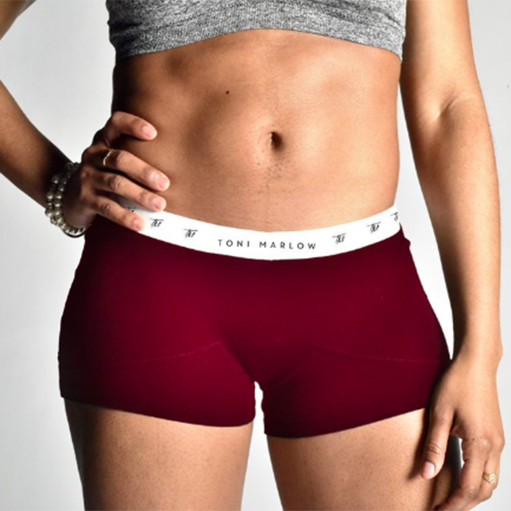 A person wearing a grey crop top and burgundy boxer briefs