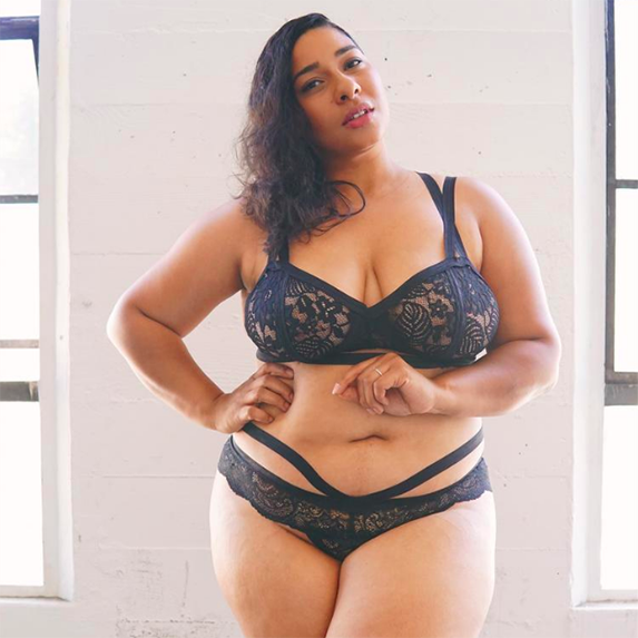 A woman with her hand on her hip wearing charcoal grey lacy lingerie