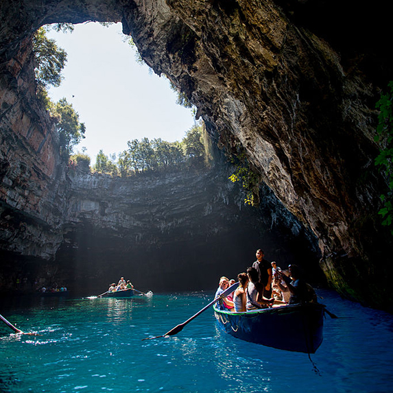 A group of people paddling a boat through the sunken lake in Melissani Cave