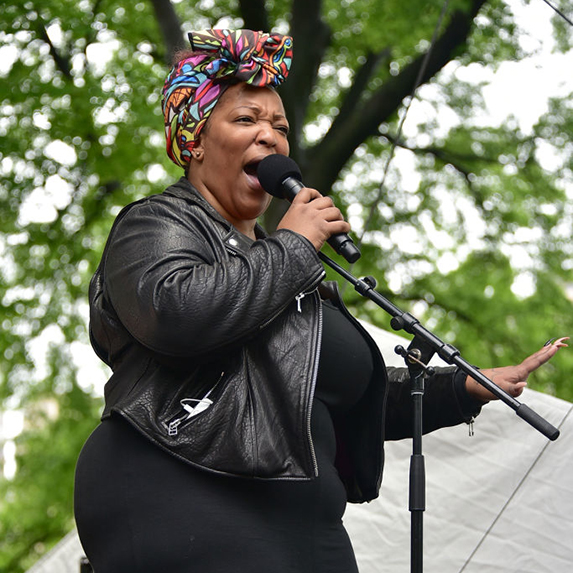 Frenchie Davis performs in a colourful head scarf and black leather jacket and pants