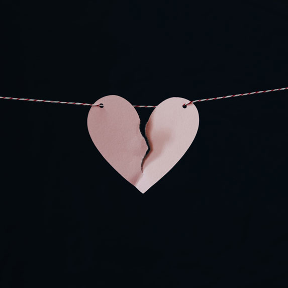 A ripped paper heart hanging by a thread