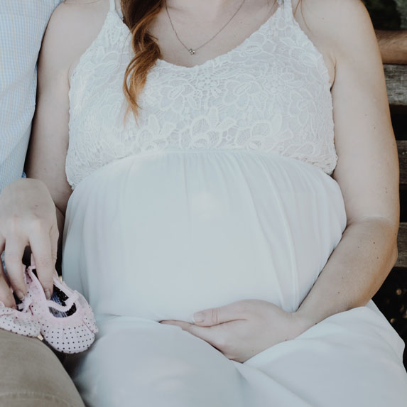 A pregnant woman sitting, holding her belly