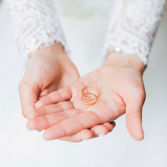 A closeup of a woman's hands holding two wedding bands