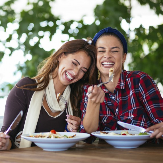 two women laughing and eating