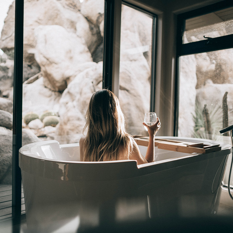 Woman sitting in a tub holding a glass of wine