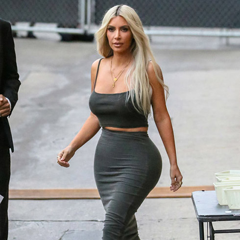 Kim Kardashian walking outside wearing a body hugging skirt and tank top.