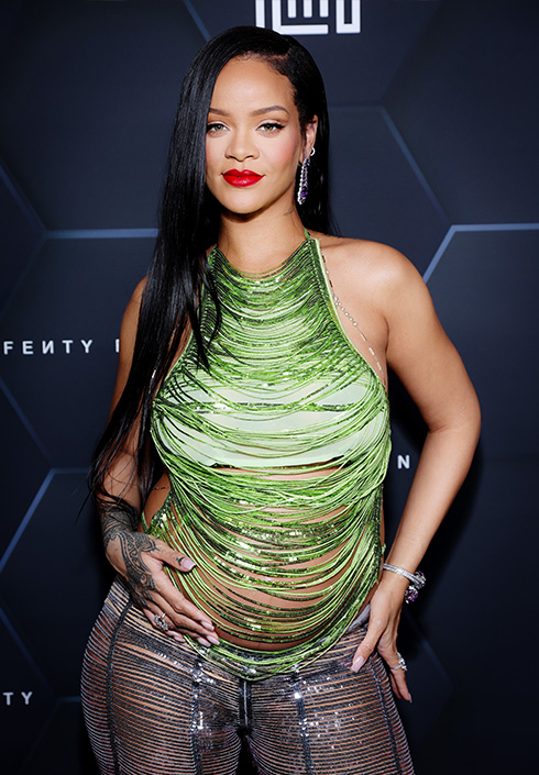 Rihanna wearing a green beaded outfit holding her baby bump