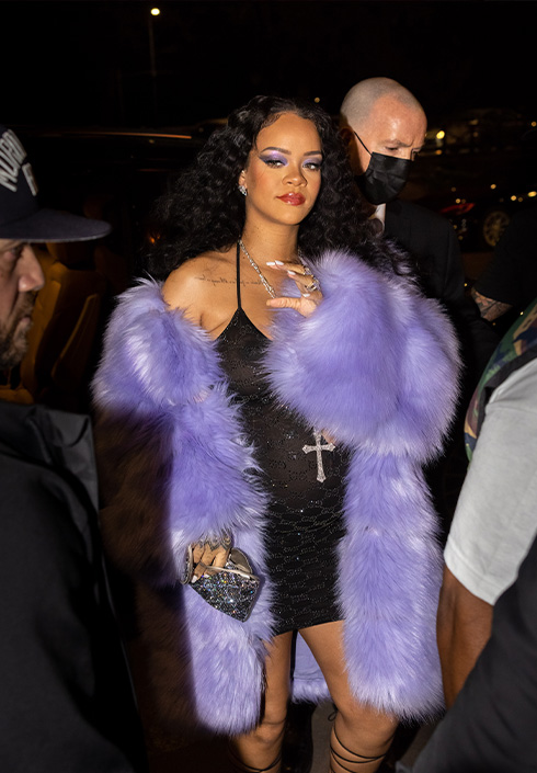 Rihanna wearing a black dress and purple fur coat
