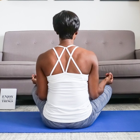 Woman wearing comfy clothes doing yoga and meditating at home.