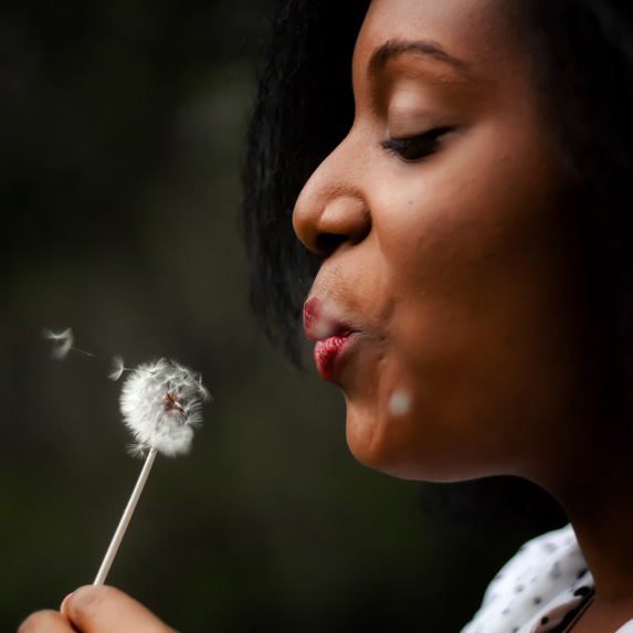 Woman blowing on a dandelion