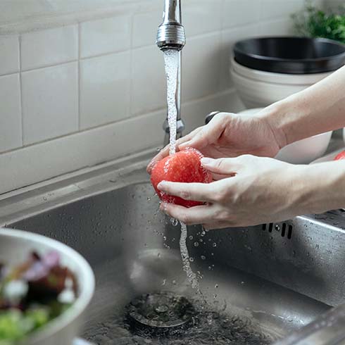 hands washing an apple at kitchen sink