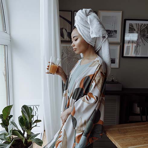 Young Asian woman wearing a printed robe and holding a glass.