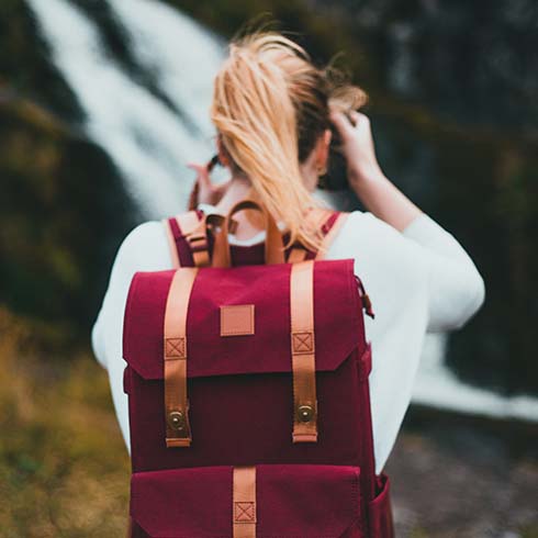 Young woman hiking while wearing red backpack