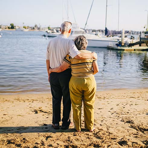 Older couple standing on beach.