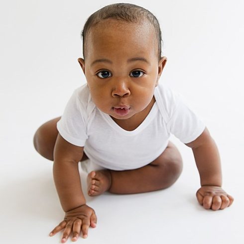 Cute, big-cheeked baby in a white t-shirt, mid-crawl.