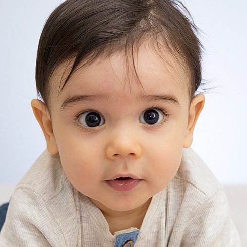 Adorable Middle Eastern baby with big brown eyes looking at the camera in wonder