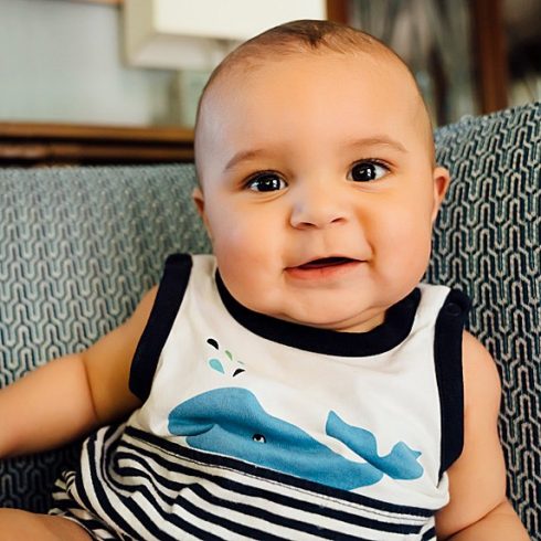 Biracial baby smiling at a camera in a whale t-shirt
