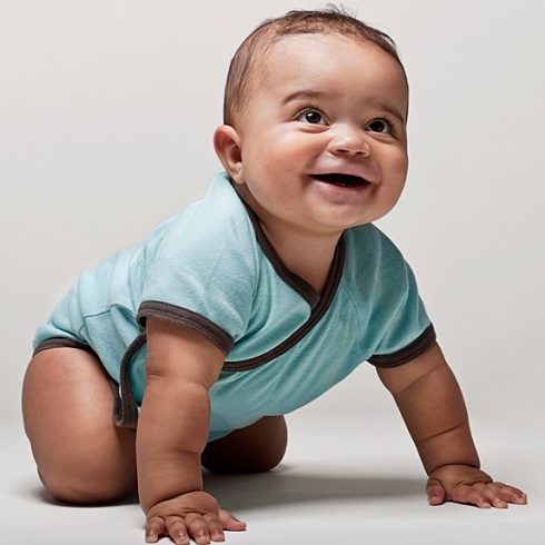 Biracial baby boy crawling and smiling looking up