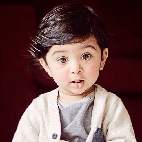 Adorable Middle Eastern toddler with side-swept dark brown hair and big brown eyes