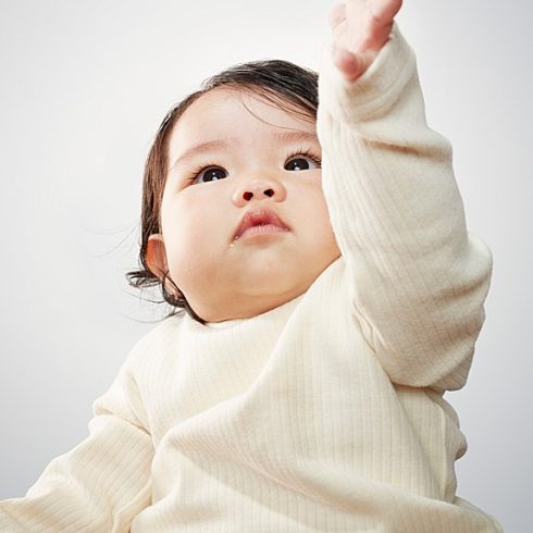 Asian baby boy holding out his hand and looking upward
