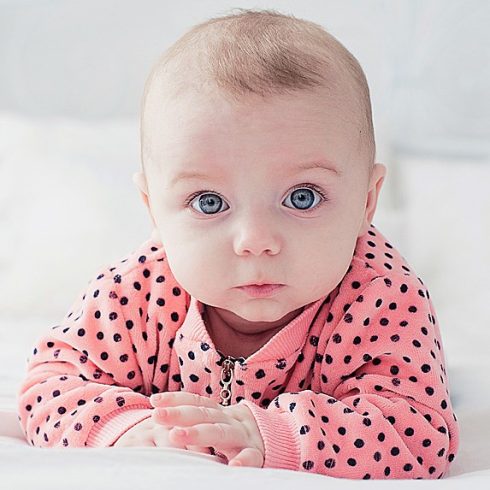 Adorable blue-eyed baby girl looking at the camera.