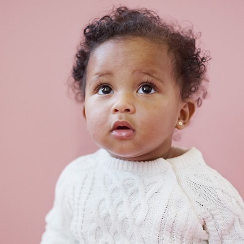 Sweet black baby girl with short curly hair and big brown eyes looking up.