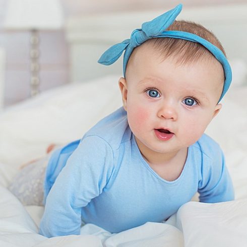 White baby girl in blue with a bow on her head