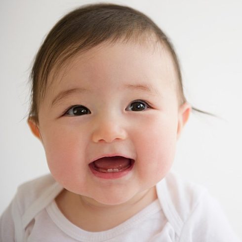 Smiling biracial baby with baby teeth showing
