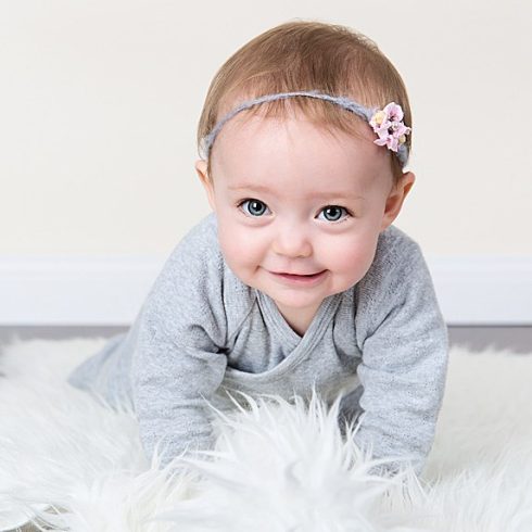 Crawling white baby girl with short light brown hair and blue eyes