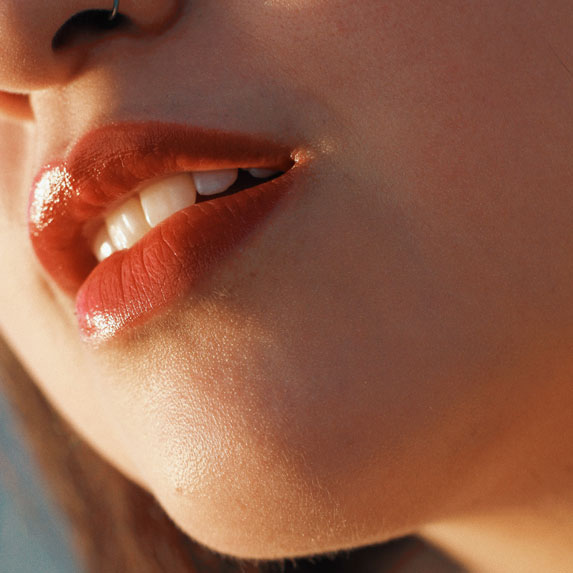 A close-up of a woman's mouth with red lipstick on