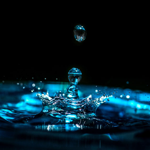 Water droplets falling into a pool of water and splashing