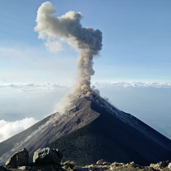 A volcano erupting creating a cloud of smoke at the top