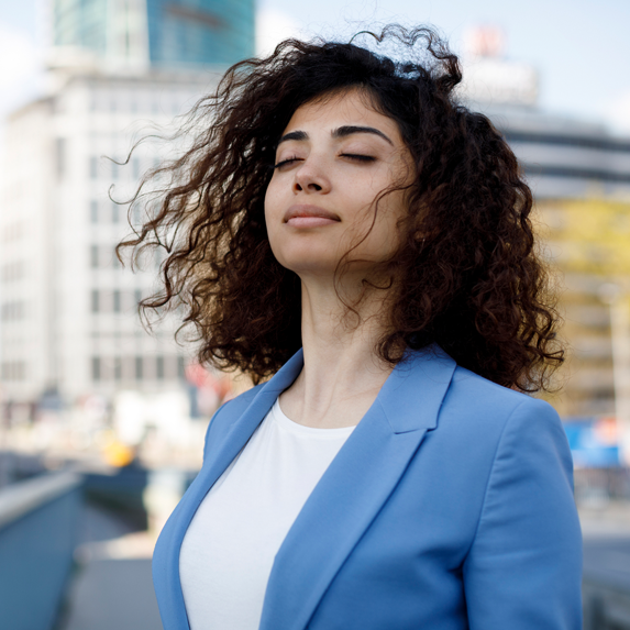 Business woman breathing in air on the rooftop with her eyes closed